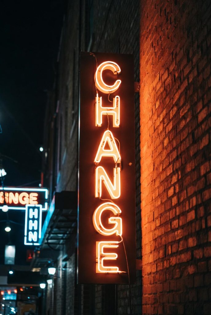 Neon change sign against a brick wall